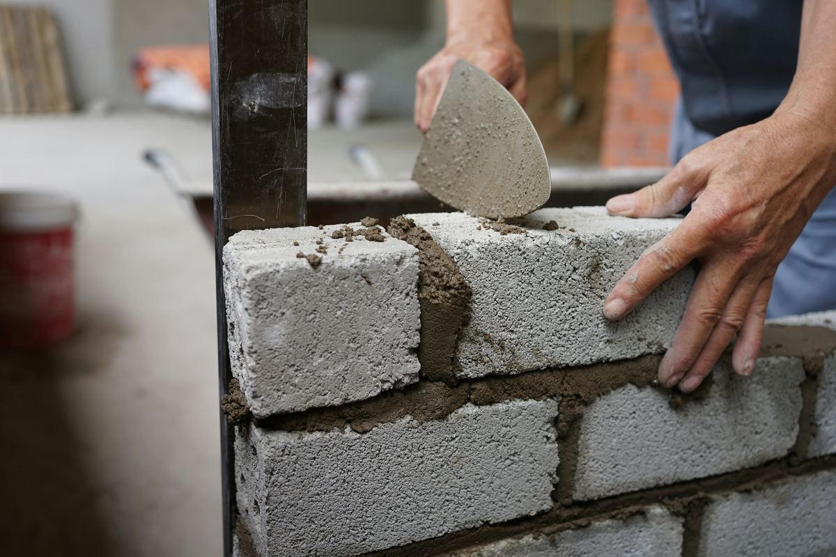 Handen leggen betonblokken in mortel