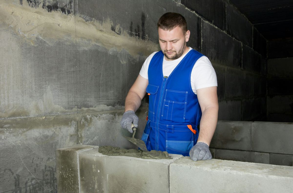 Metselaar metselt een binnenmuur in betonblokken