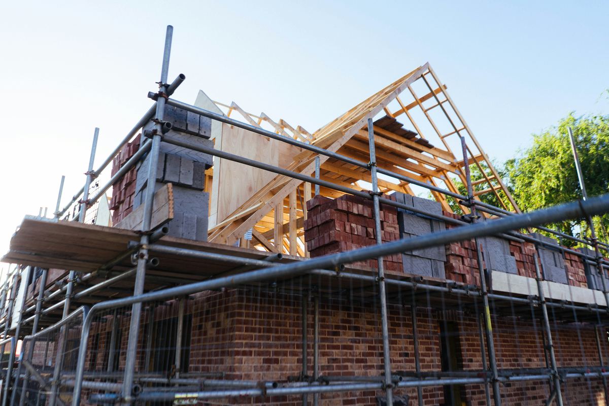 Ruwbouw van een woning in baksteen, met stelling en dakspanten